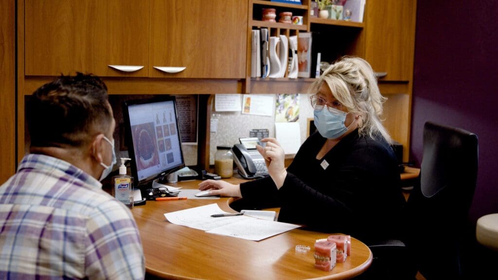 a woman wearing a mask and sitting at a desk